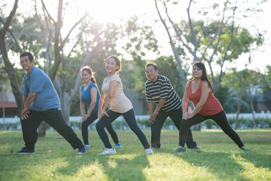 Smiling mature people doing morning exercises in a group